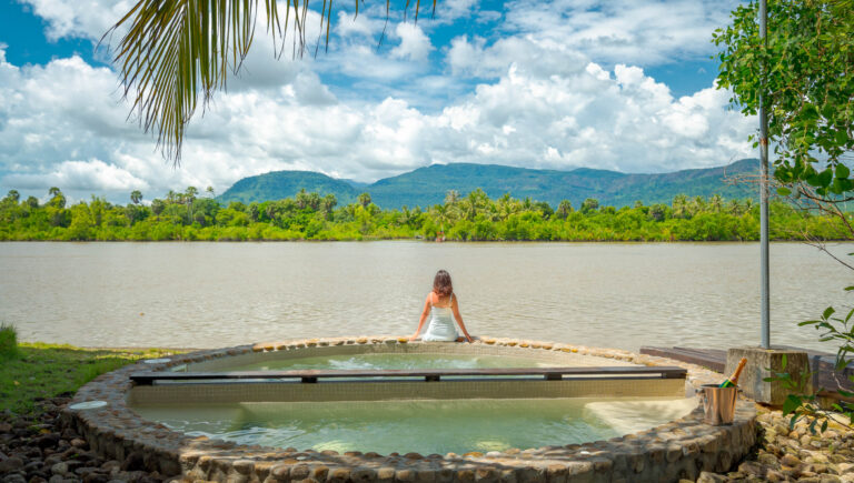 Guest relaxing on river platform at Kampot resort with mountain views – hotel photography Cambodia