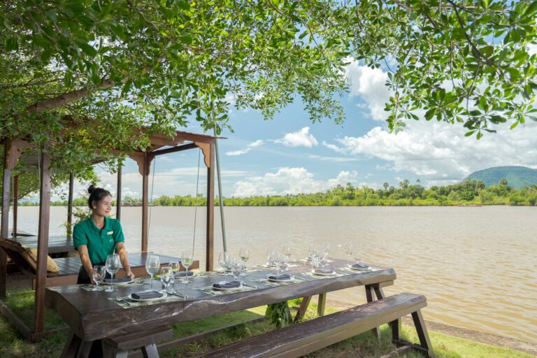 Outdoor dining area at Kampot resort by the river with shaded seating and scenic views – hotel photography Cambodia