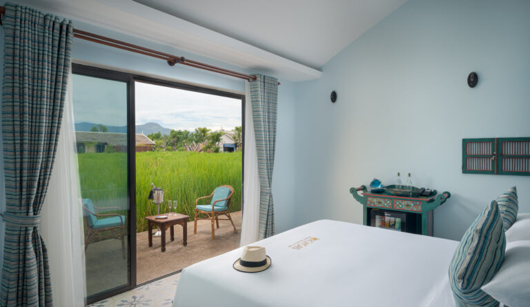 Bright resort bedroom in Kampot with large windows and outdoor terrace view