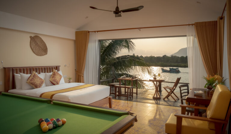 Bright resort bedroom in Kampot with large windows and outdoor terrace view