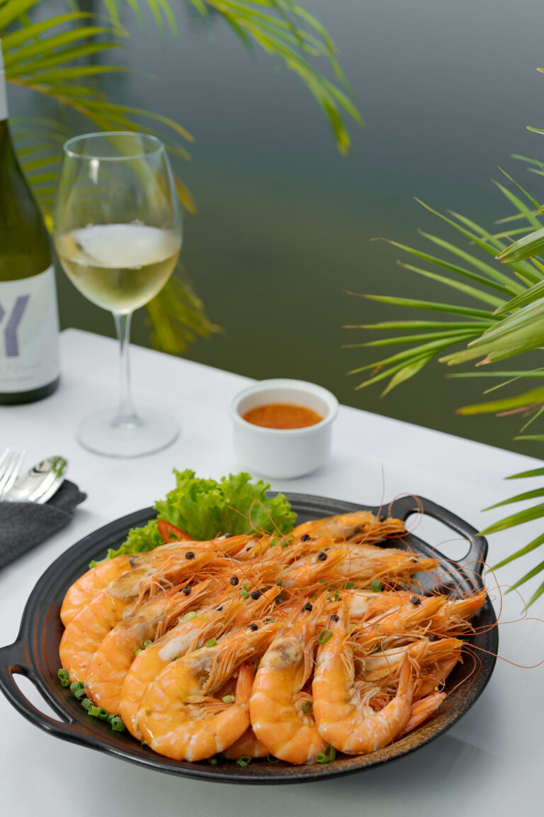 Prawn dish with wine at resort restaurant in Kampot with outdoor dining setup – hotel photography Cambodia