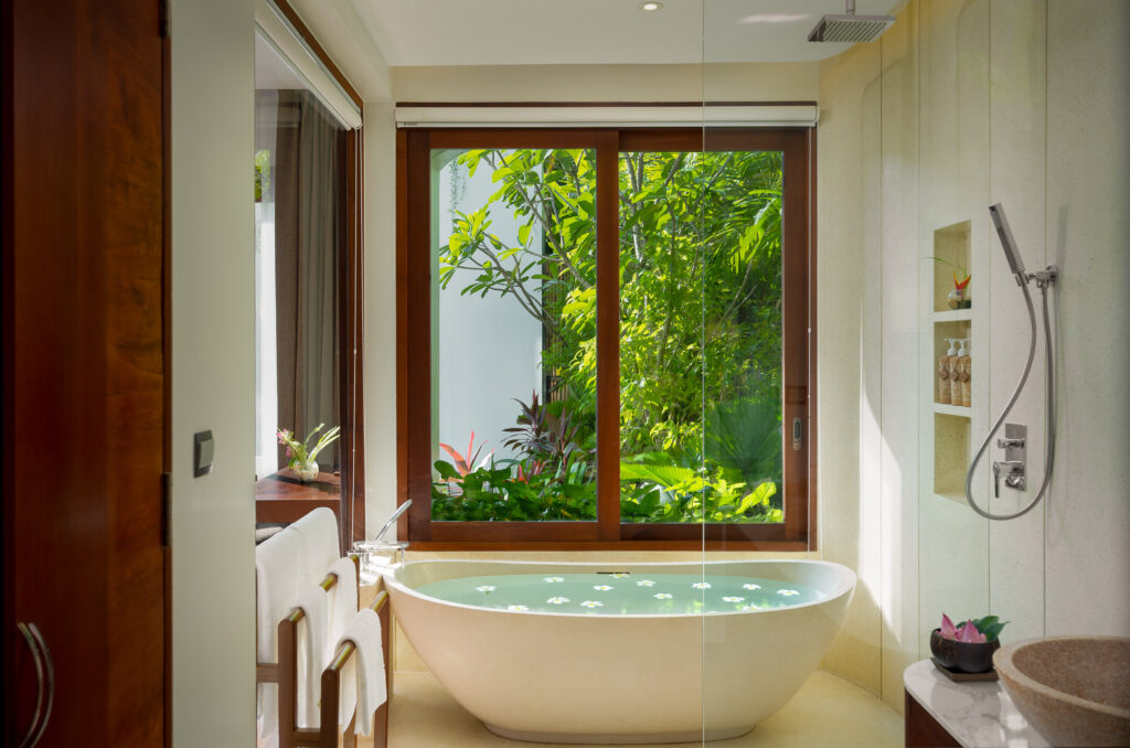 Hotel bathroom amenities and bathtub prepared for professional photoshoot with natural light and garden view