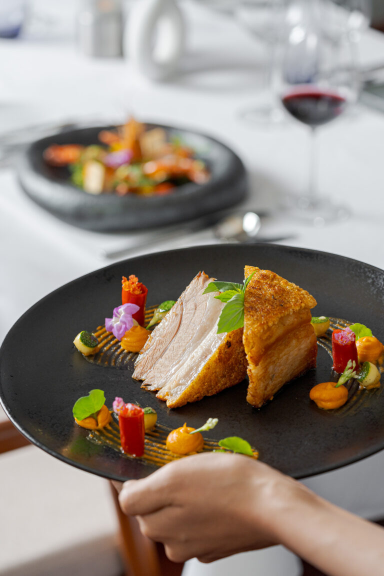 Server presenting gourmet chicken dish at Pergola Restaurant