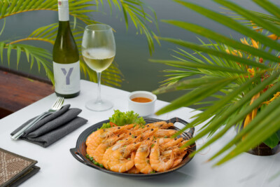 Prawn dish with wine at resort restaurant in Kampot with outdoor dining setup – hotel photography Cambodia